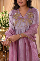 Woman wearing a purple embroidered dress with gold details indoors.