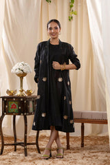 A woman in a black Indo-Western dress, paired with a matching coat featuring pichwai motifs.