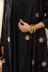 A woman in a black Indo-Western dress, paired with a matching coat featuring pichwai motifs.