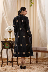 A woman in a black Indo-Western dress, paired with a matching coat featuring pichwai motifs.