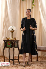 A woman in a black Indo-Western dress, paired with a matching coat featuring pichwai motifs.