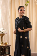 A woman in a black Indo-Western dress, paired with a matching coat featuring pichwai motifs.