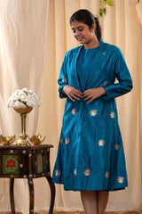 A woman in a blue Indo-Western dress with a matching coat is standing in front.