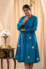 A woman in a blue Indo-Western dress with a matching coat is standing in front.