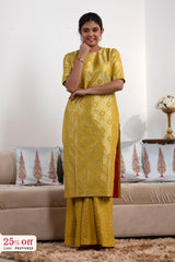 Woman wearing a yellow traditional outfit with a beige sofa and decorative pillows in the background