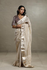 Woman wearing a Tissue silk party wear saree for a wedding and festival look against a plain background