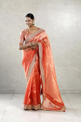 Woman wearing an orange saree with a plain background