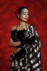 A woman wearing a black and silver party wear saree against a red background representing the Best Saree look for parties and weddings