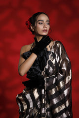 A woman wearing a black and silver party wear saree against a red background representing the Best Saree look for parties and weddings