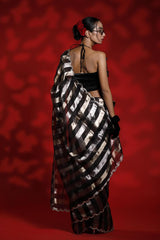 A woman wearing a black and silver party wear saree against a red background representing the Best Saree look for parties and weddings