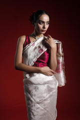 Woman wearing a red blouse with a white saree against a red background
