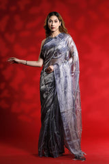 A woman wearing a shiny silver party wear saree with a red background