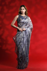A woman wearing a shiny silver party wear saree with a red background