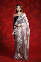 A woman wearing a light pink party wear saree with a red background