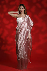 A woman wearing a pink party wear saree with a floral blouse against a red background