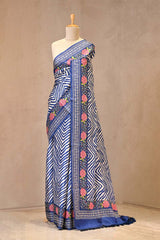 Close up of Blue and White Tussar Silk Saree showing digital printed wavy chevron print on the body and floral cross-stitch embroidery on the border.