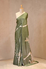 Close up of Matte Green Tussar Silk Saree showing plain body, floral tissue applique and pitta zari work on the pallu with a scalloped border.
