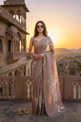 Woman in a beige tussar applique saree standing in front of an architectural structure with a sunset in the background
