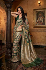 Woman wearing a Bottle Green Banarasi Katan Silk Saree with Rangkat weave and a rich gold zari border, holding a clutch in a heritage setting.
