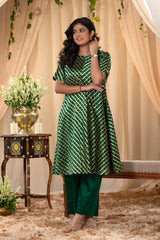 A woman in a green traditional kurti co-ord set, standing in a decorated indoor setting.