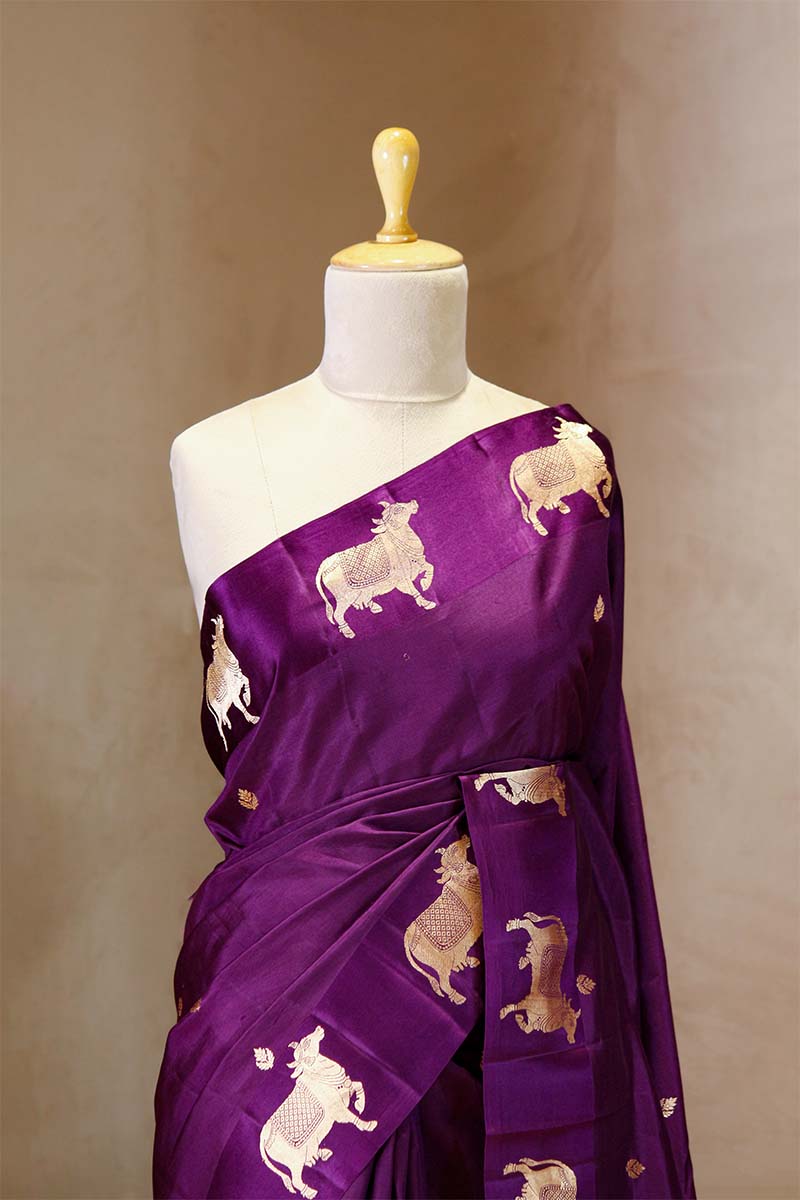 A purple Banarasi silk saree with Pichwai border for Navratri, Diwali, Durga Puja, and weddings, displayed on a mannequin. 