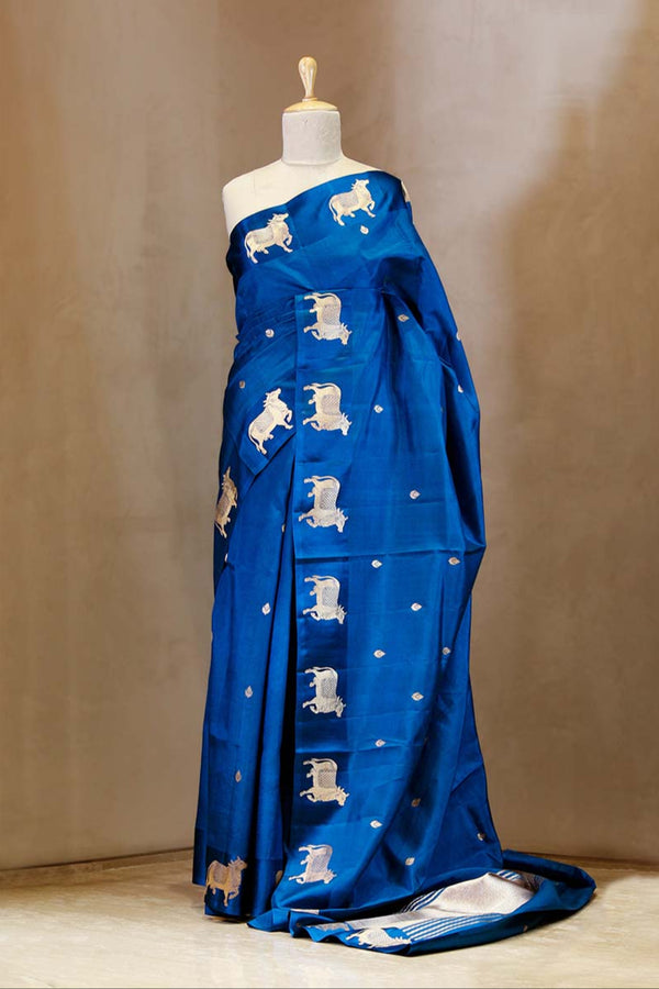 A blue Banarasi silk saree with gold zari border for Navratri, Diwali, Durga Puja, and weddings, displayed on a mannequin. 