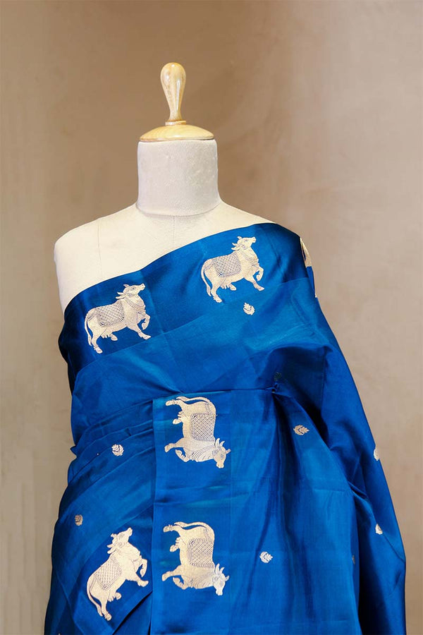 A blue Banarasi silk saree with gold zari border for Navratri, Diwali, Durga Puja, and weddings, displayed on a mannequin. 