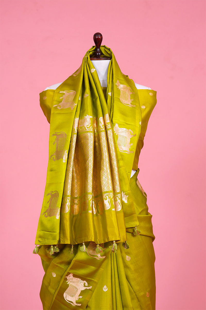 A henna green Banarasi silk saree with zari border for Navratri, Diwali, Durga Puja, and weddings, displayed on a mannequin. 