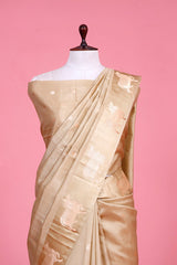 A beige Banarasi silk saree with gold zari border for Navratri, Diwali, Durga Puja, and weddings, displayed on a mannequin. 
