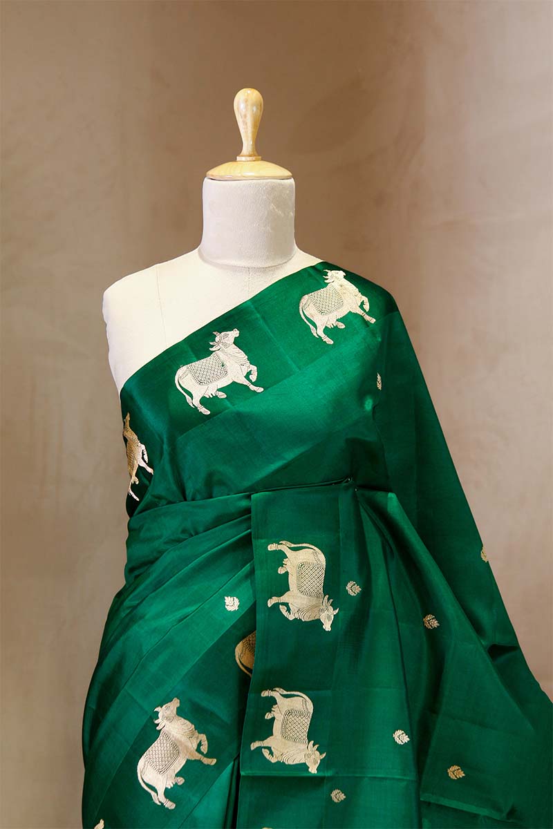 A green Banarasi silk saree with gold zari border for Navratri, Diwali, Durga Puja, and weddings, displayed on a mannequin. 