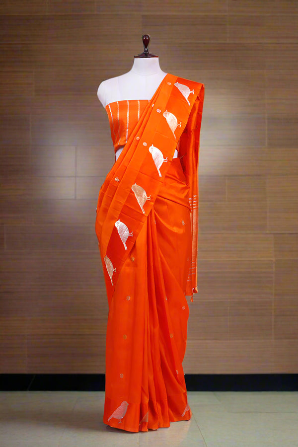 Orange saree with white patterns on a mannequin against a pink background