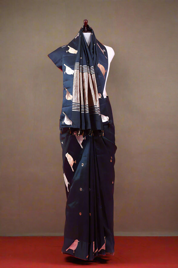 Navy blue saree with white patterns on a mannequin against a pink background