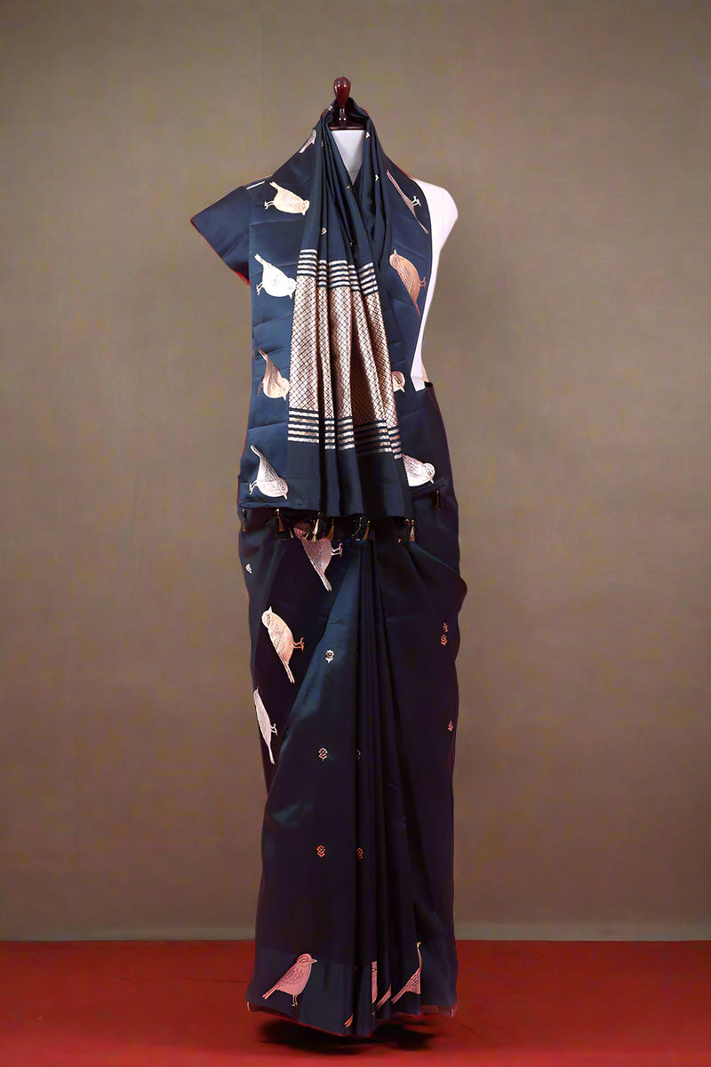 Navy blue saree with white patterns on a mannequin against a pink background