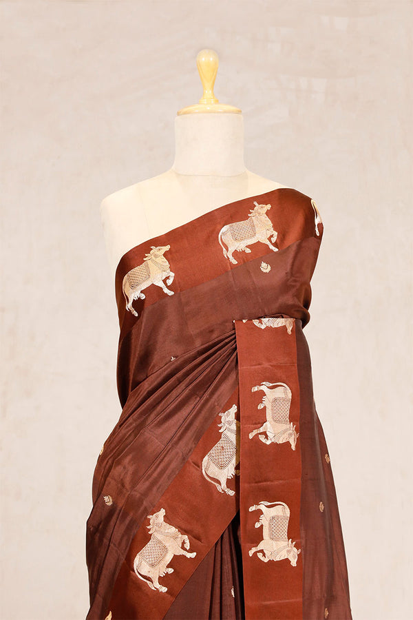 A dark grey Banarasi silk saree with Pichwai border for Navratri, Diwali, Durga Puja, and weddings, displayed on a mannequin. 
