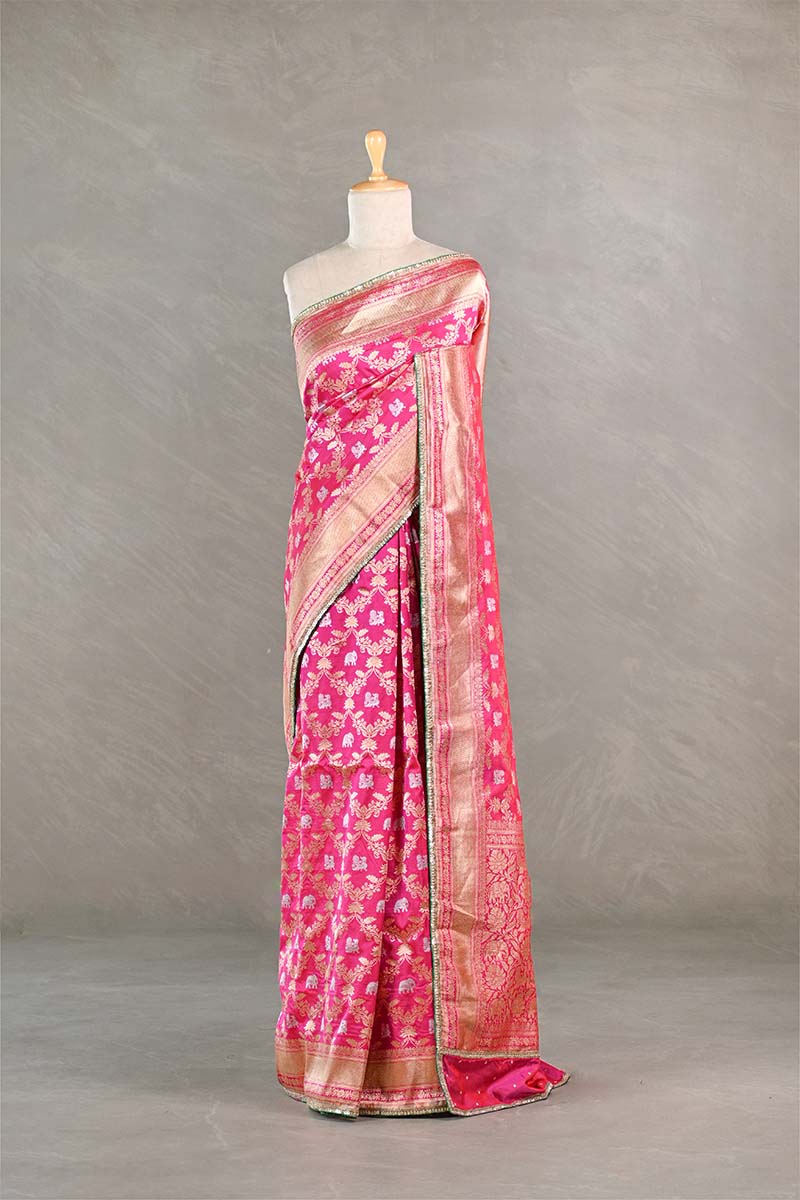 Pink saree with a floral pattern on a mannequin against a gray background