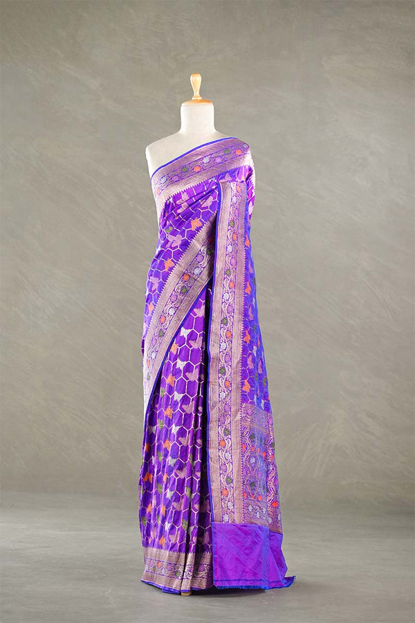 Purple Banarasi silk saree with multicolor meena work, the saree is  draped on a mannequin against a gray background