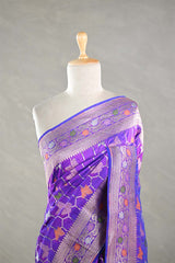 Purple Banarasi silk saree with multicolor meena work, the saree is  draped on a mannequin against a gray background