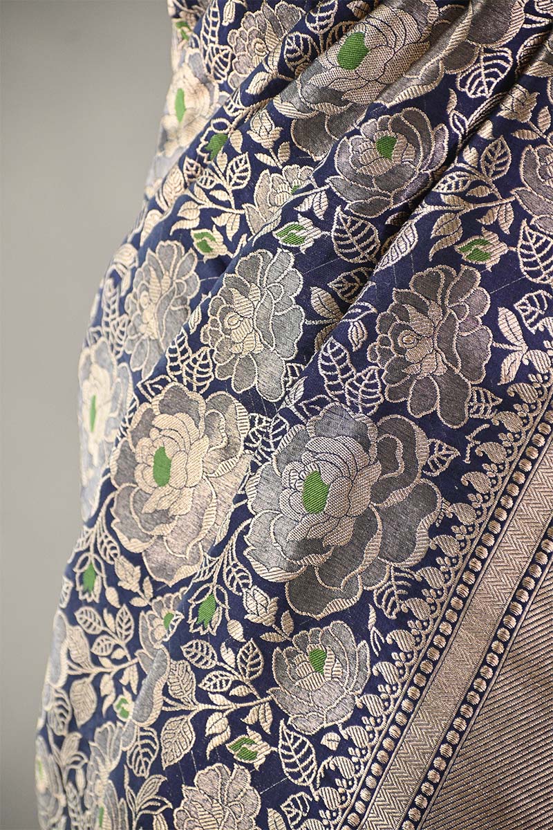 Close-up of a floral patterned fabric with green accents on a blue background.