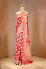 Red saree with white patterns on a mannequin against a beige background