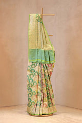 Traditional saree with green and floral patterns on a wooden stand against a beige background