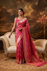 Woman in a pink banarasi saree standing in front of a classical painting with a candlelit scene. Silk MArk Certified Pink Banarasi Saree