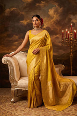 Woman in a yellowish green banarasi silk saree sitting on an ornate chair with a dramatic background