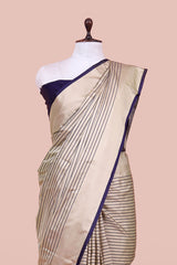 Beige saree with blue border on a mannequin against a beige background