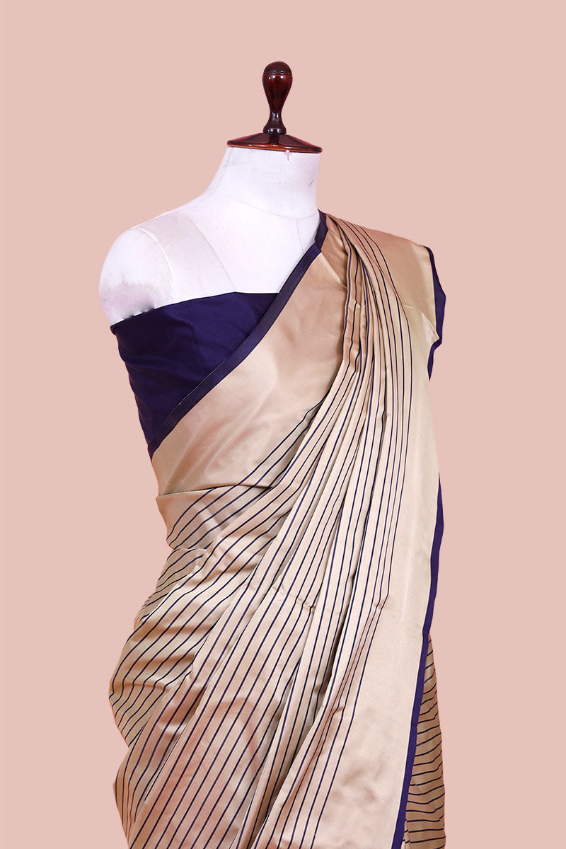 Beige saree with black stripes and blue border on a mannequin against a beige background