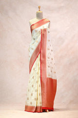 White saree with red border on a mannequin against a light pink background