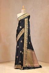 Close up of Black Semi Satin Silk Saree showing gold zari woven pakshi motifs and a Mrigvan-inspired deer and tree border.