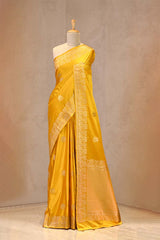 Close up of Yellow Semi Satin Silk Saree showing gold zari woven pakshi motifs and a Mrigvan-inspired deer and tree border.