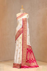 Close up of White and Pink Semi Satin Silk Saree showing gold zari woven rose buti on white body and gold zari floral patterns on contrasting pink border.
