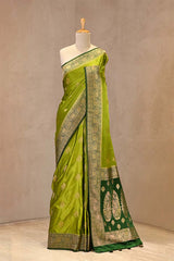 Close up of Peridot Green and Green Semi Satin Silk Saree showing gold zari woven rose buti on white body and gold zari floral patterns on contrasting pink border.
