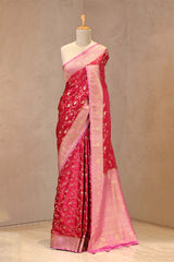Close up of Pink Semi Satin Silk Saree showing gold zari woven floral jaal on pink body and gold zari floral patterns on contrasting border.
